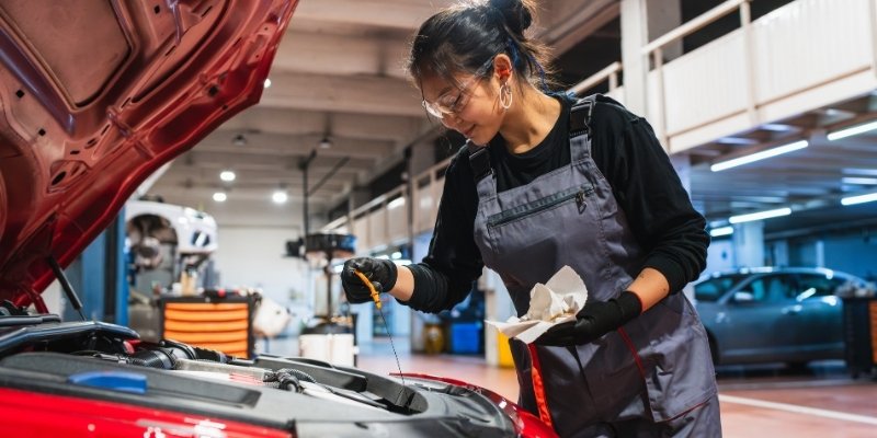 mechaniczka sprawdzająca poziom oleju w samochodzie