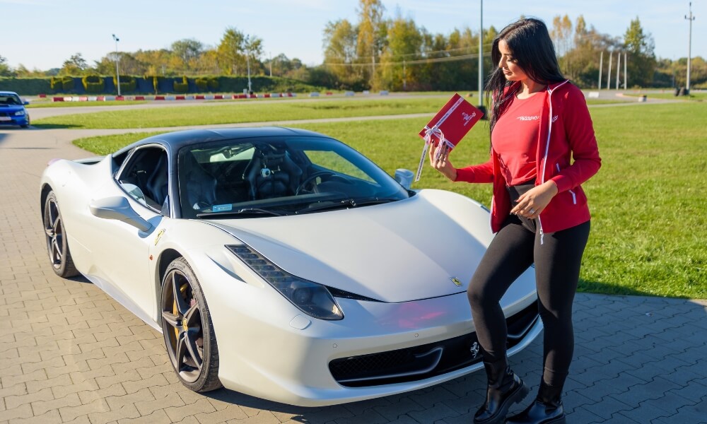 dziewczyna przy ferrari italia 458 z voucherem w ręce